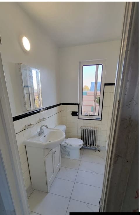 The same bathroom finished with new tile flooring, vanity, toilet, mirror and ceiling light