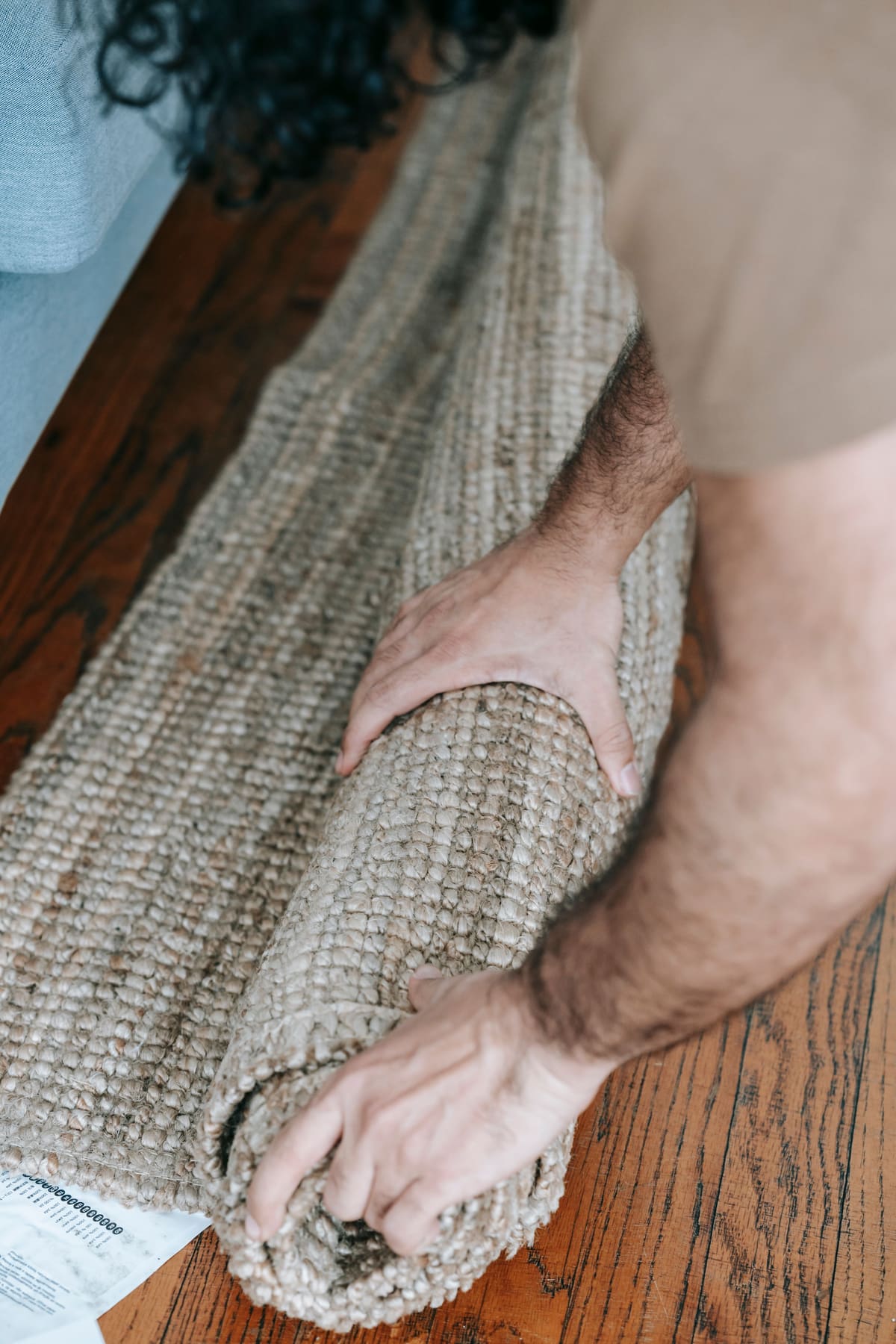 Hands rolling out carpet across a bare floor
