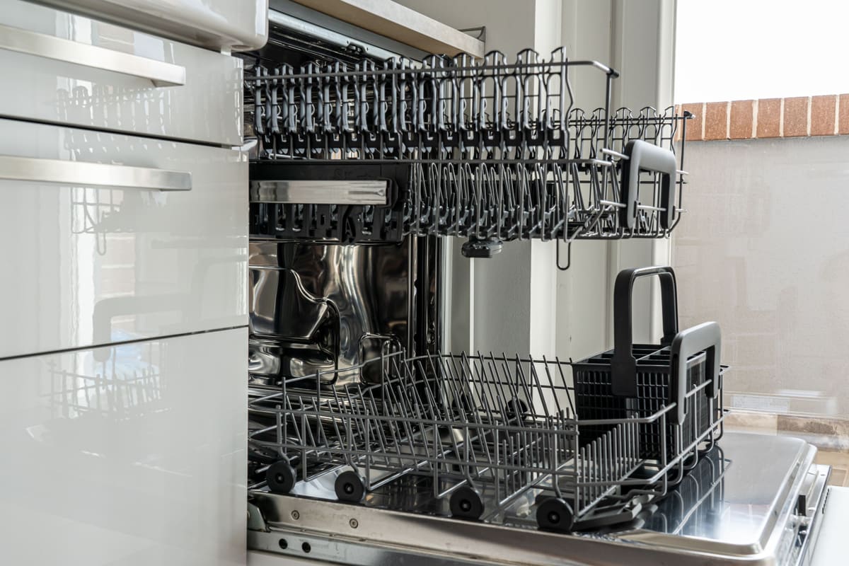 Dishwasher door open showing the racks and the drain filter