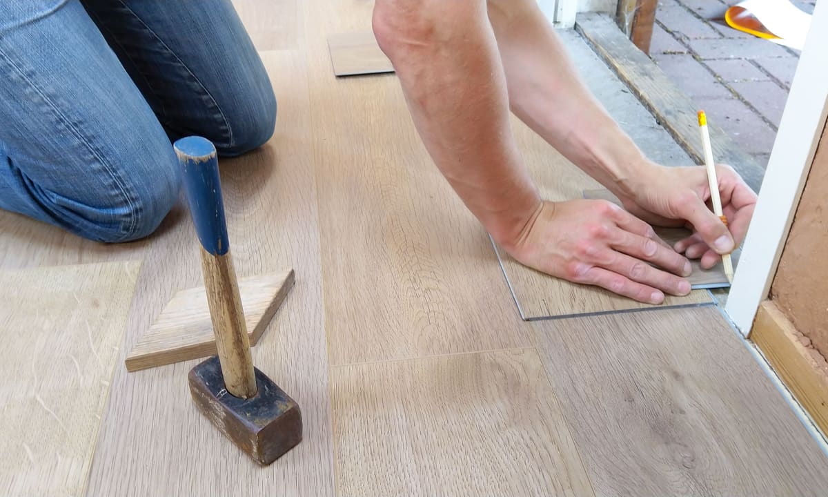 Vinyl plank being scored and cut to length on the floor