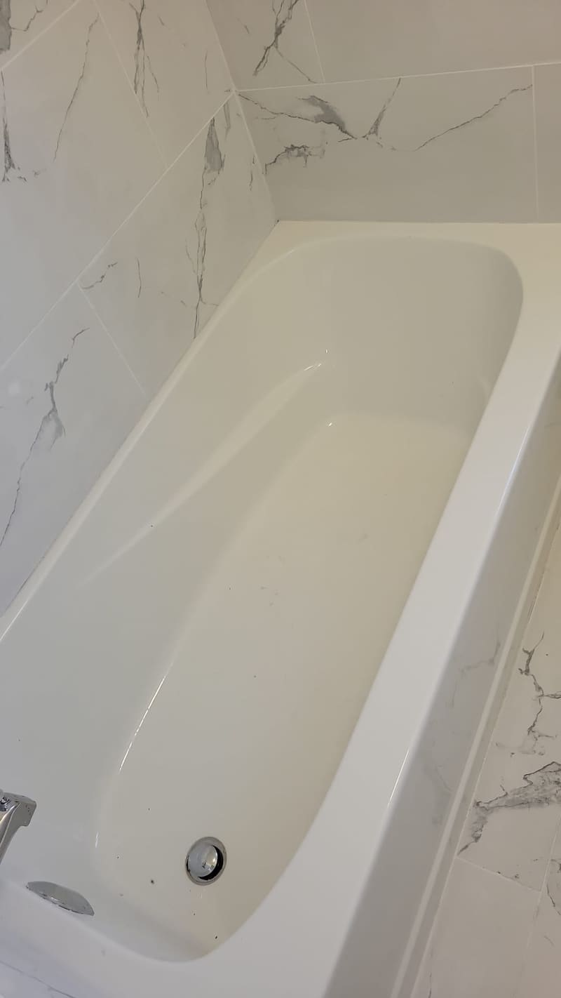 Tub set level and sealed to the surround so water runs back into the bath, not behind it.