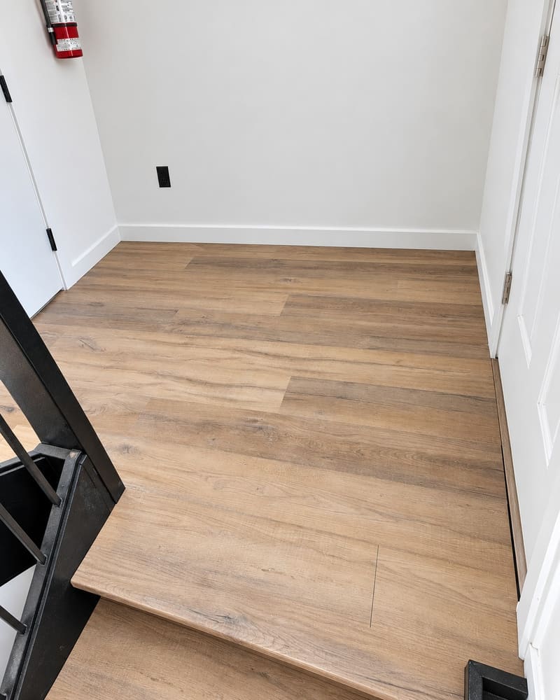 Laminate flooring laid through an upstairs landing, scribed in tight to the staircase.