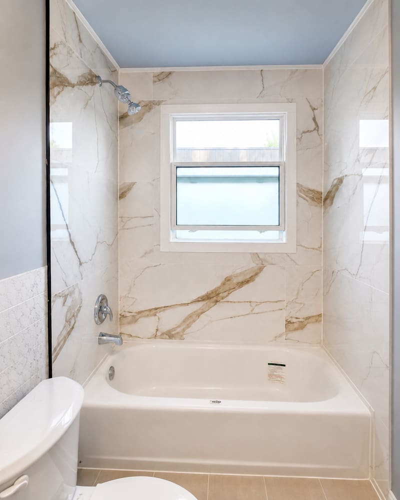 Large-format marble-look tile run around a new soaker tub, floor to ceiling.
