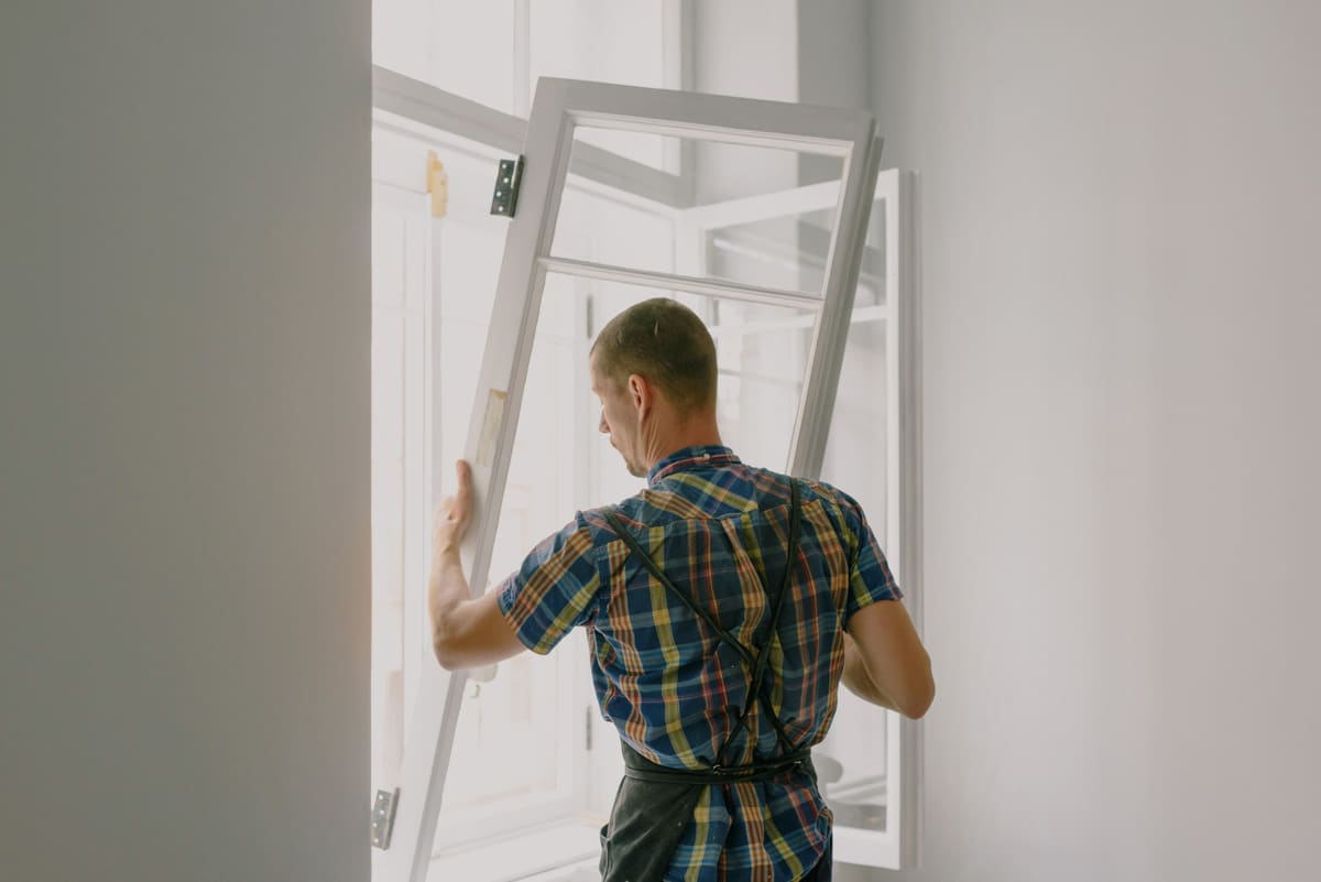 Tradesperson lifting a new interior door into an open door frame