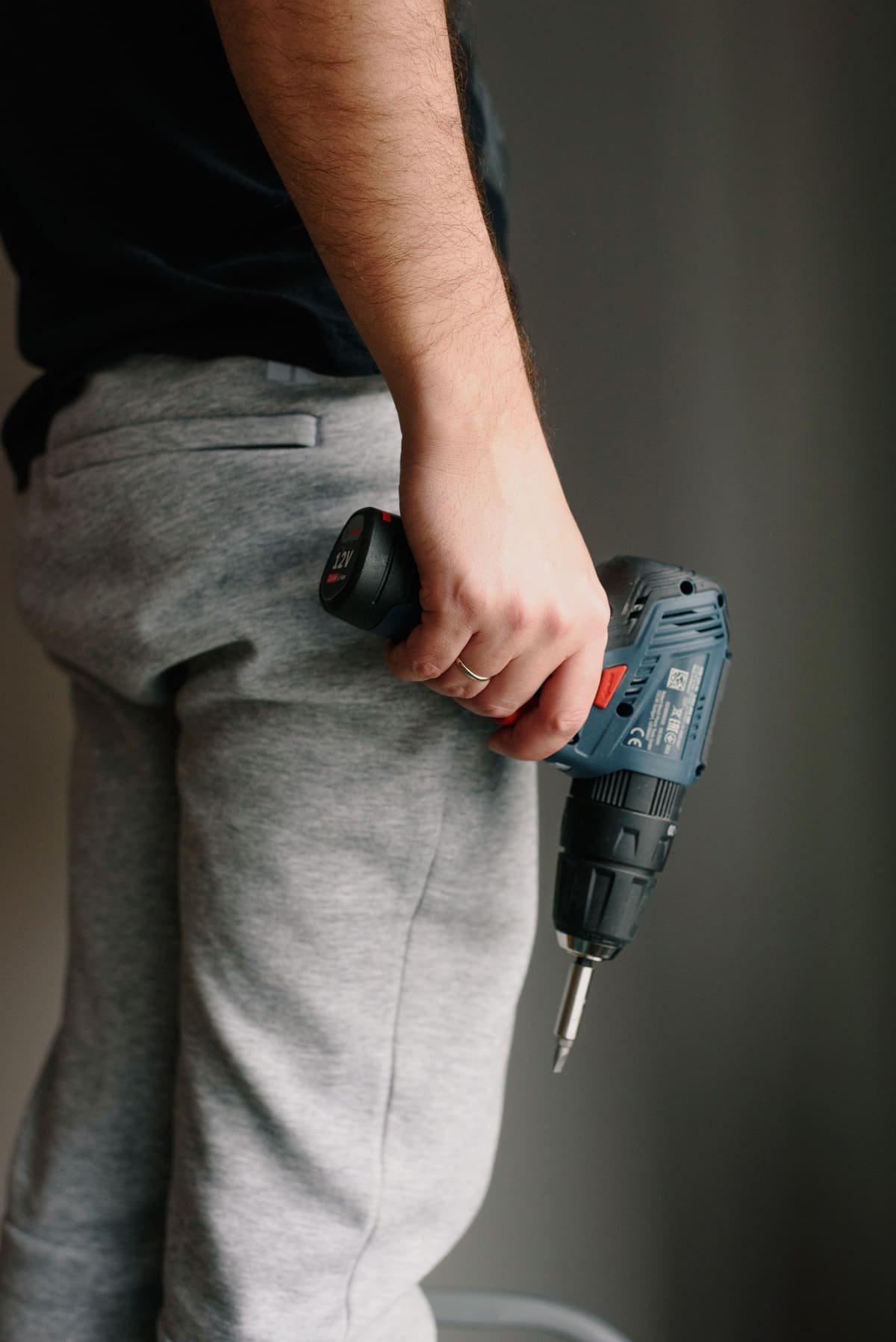 Handyman holding a cordless drill at his side inside a room being worked on