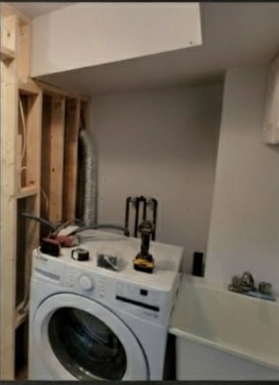 The rebuilt laundry space with a front-load washer in place and new dryer ducting run