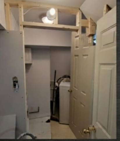 Laundry closet with the header framing exposed and the old door still hanging
