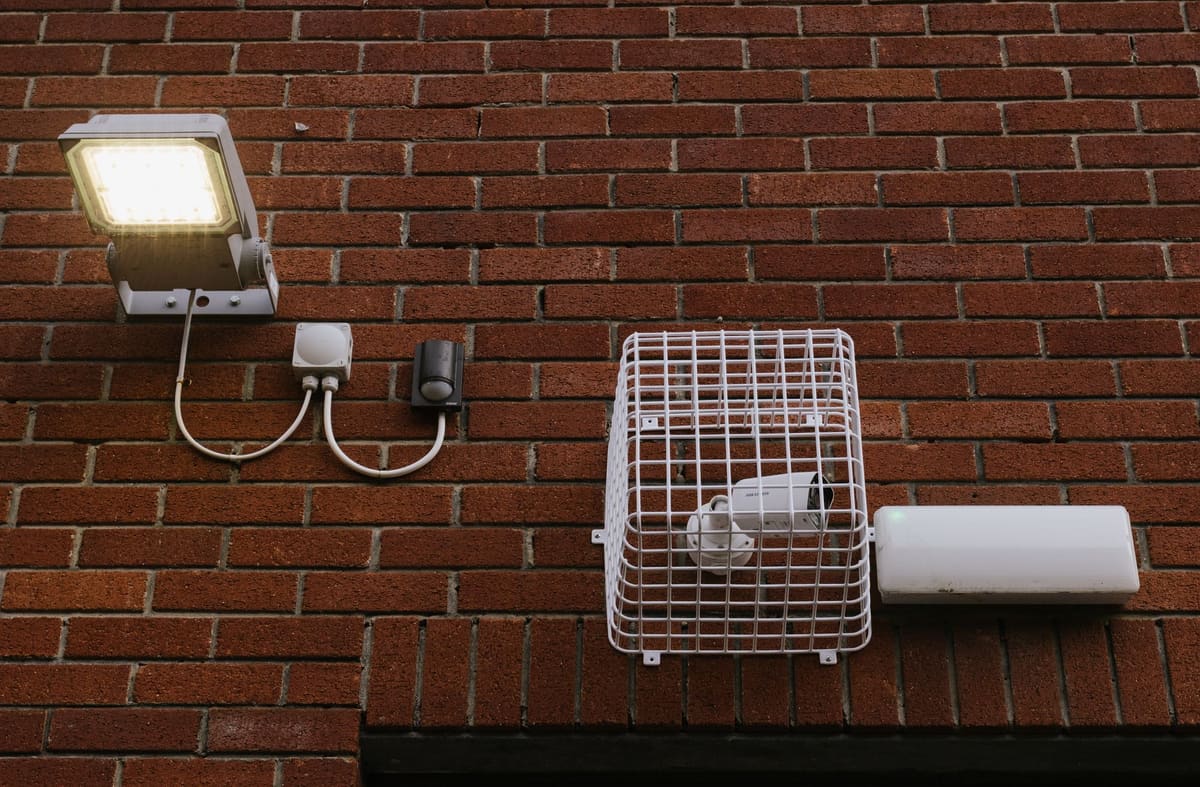 Security camera and motion light mounted on a house brick wall