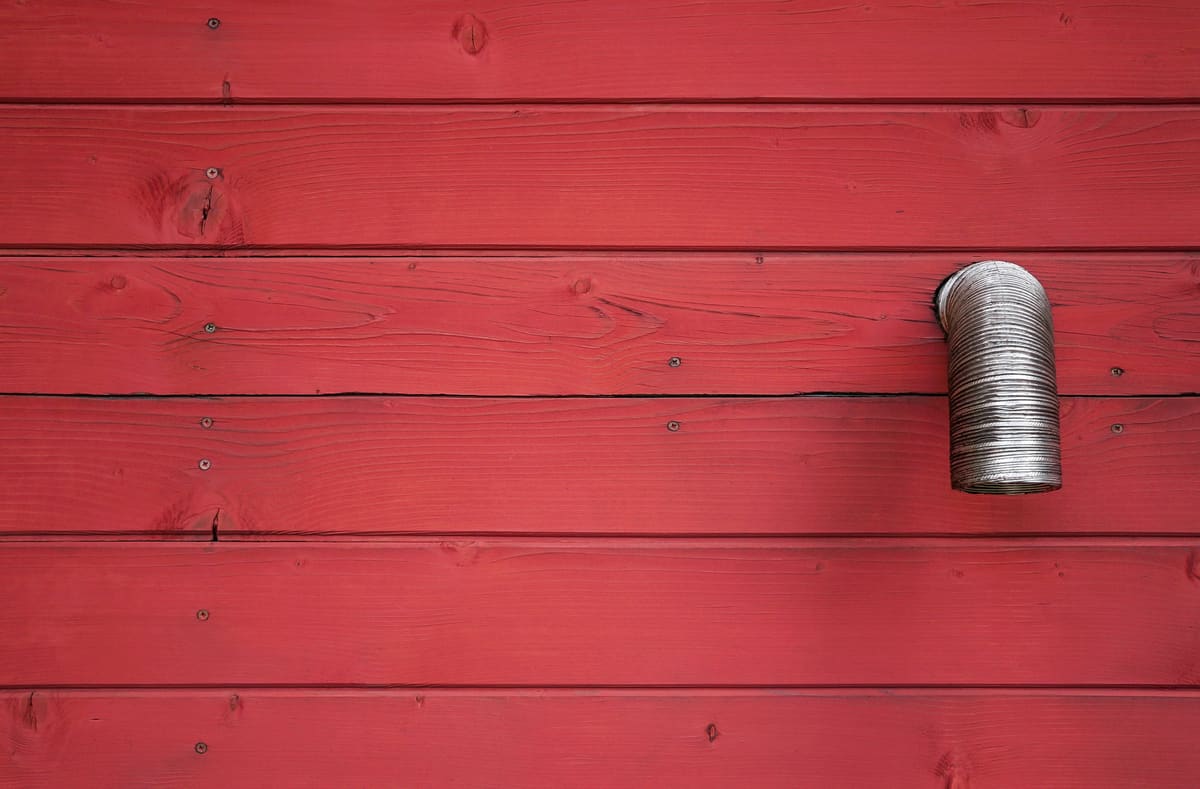 Painted board siding with a vent penetration sealed into it