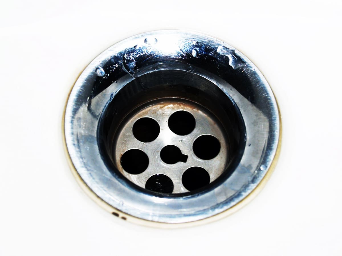 Close-up of a chrome sink drain with water beginning to pool around the edges