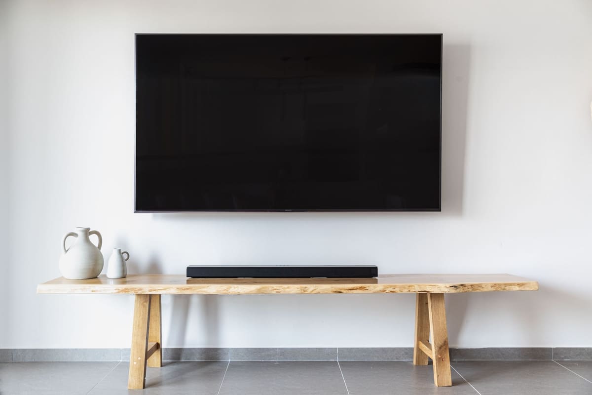Flat screen television mounted flush on a wall above a low wooden console