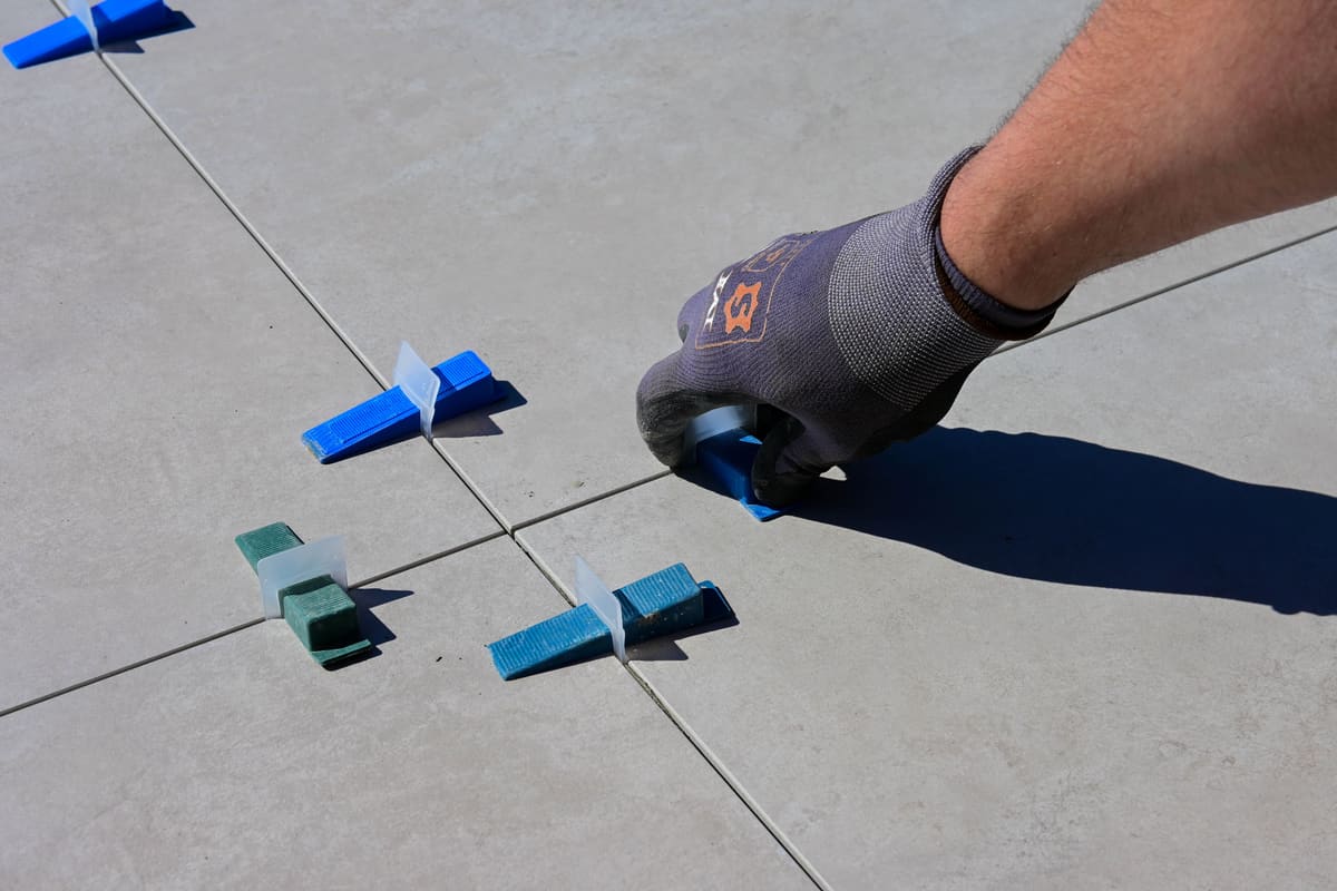 Floor tile being set with levelling clips and spacers