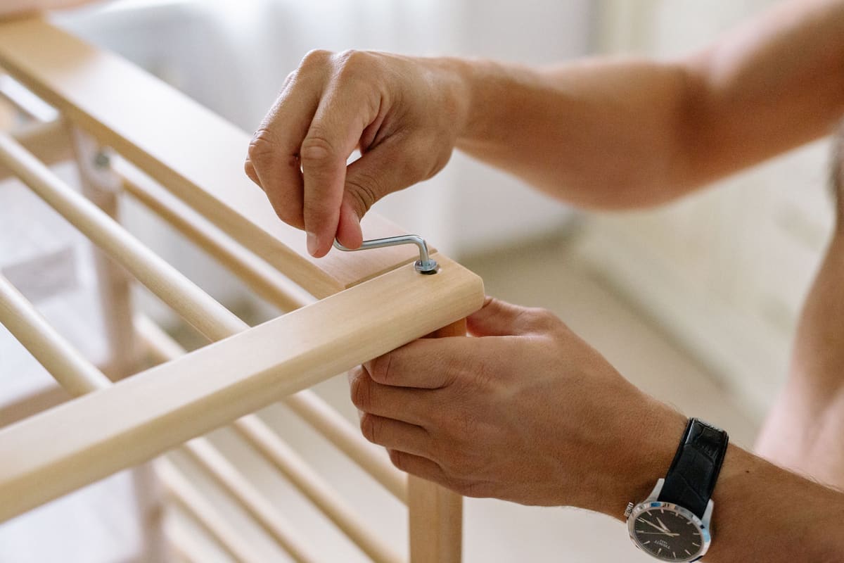Hands tightening an allen bolt while assembling a flat-pack timber frame